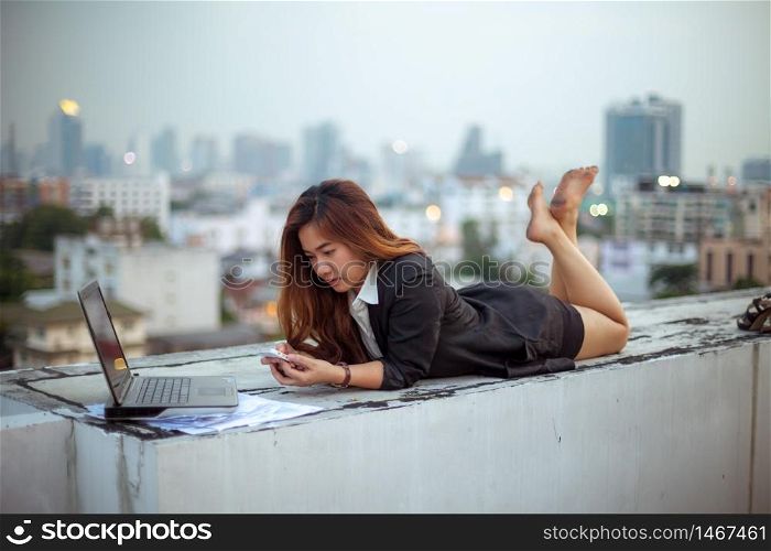 Asian woman using her mobile phone, city skyline night light background