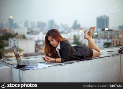Asian woman using her mobile phone, city skyline night light background