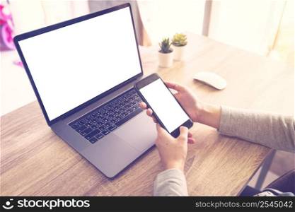 asian woman using laptop computer do online activity and holding phone on wood table at home office.