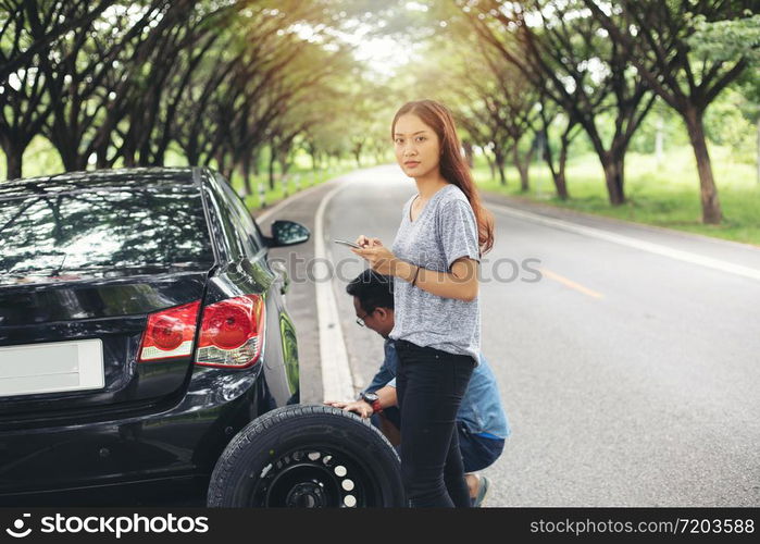 Asian woman using mobile phone while looking and Stressed man sitting after a car breakdown on street