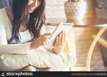 Asian woman using smart tablet shopping online website on smartphone with smiling face. Happiness asian woman holding cellphone checking mail from online shopping website read Blog vlog social media
