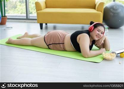 Asian woman using tablet and. wearing headphone for listening music and She is exercising at home ,Asian girl enjoy eating food