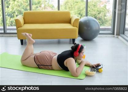 Asian woman using tablet and. wearing headphone for listening music and She is exercising at home ,Asian girl enjoy eating food