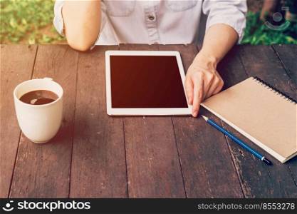 asian woman using tablet on table and coffee in garden with vintage toned.