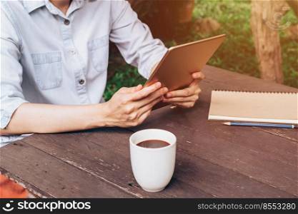 asian woman using tablet on table and coffee in garden with vintage toned.