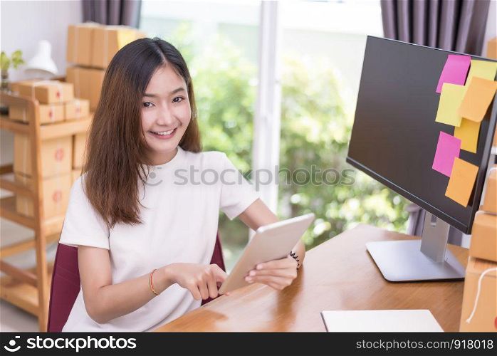 Asian woman using tablet with parcel boxes in delivery service theme. Part time and lifestyle concept