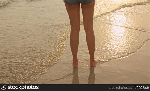 Asian woman walking on sand beach. Young happy female in bikini relax and fun walking near tropical sea when sunset while holiday, vacation, summer trip concept.