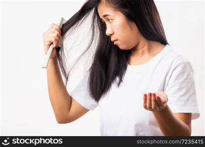 Asian woman weak hair problem her use comb hairbrush brush her hair and showing damaged long loss hair from the brush on hand, studio shot isolated on white background, Medicine health care concept