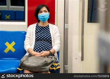 Asian woman wear face mask traveling to work by metro in city. Beautiful Young Female wear protective surgical mask for protect pandemic virus, coronavirus or covid-19 in commuter train. New normal