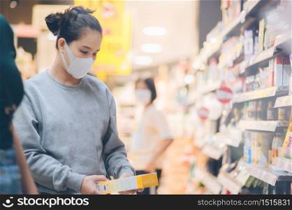 Asian woman wearing a mask in the supermarket, Panic shopping during Coronavirus covid-19 pandemic.Budget buying at a supply store.Buying freezer smart purchased household pantry groceries