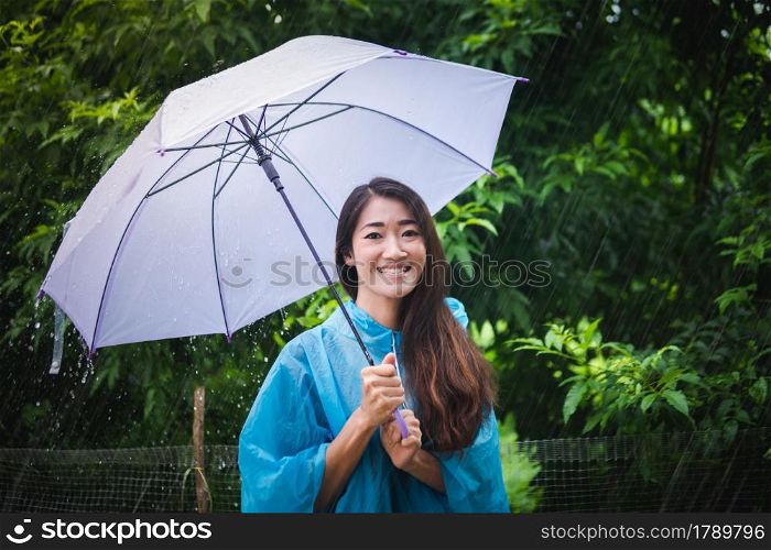 Asian woman wearing and spreading an umbrella a raincoat outdoors rainy day