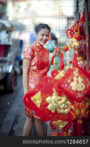 asian woman wearing chinese tradition clothes with chinese bamboo fan smiling face in yaowarat street china town of bangkok thailand