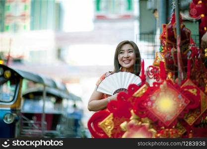 asian woman wearing chinese tradition clothes with chinese bamboo fan toothy smiling face in yaowarat street china town of bangkok thailand