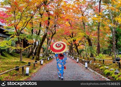 Asian woman wearing japanese traditional kimono walking in autumn park.