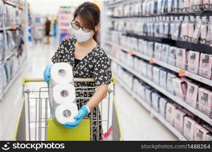Asian woman wearing protective mask and holding toilet paper during shopping in supermarket or grocery, protect coronavirus inflection. Hygiene, new normal and life after covid-19 pandemic