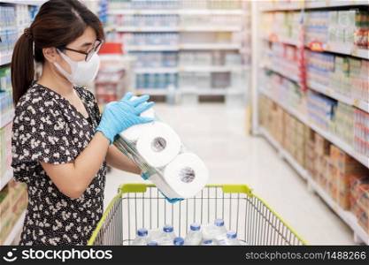Asian woman wearing protective mask and holding toilet paper during shopping in supermarket or grocery, protect coronavirus inflection. Hygiene, new normal and life after covid-19 pandemic