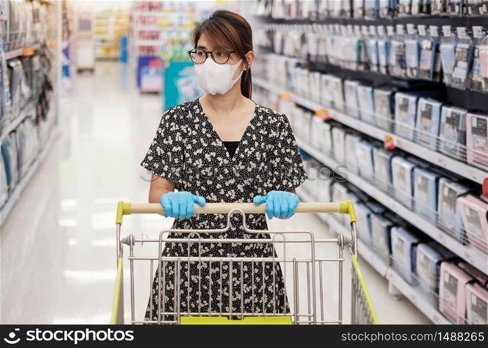 Asian woman wearing protective mask and nitrile gloves during shopping in supermarket or grocery, protect coronavirus inflection. social distancing, new normal and life after covid-19 pandemic