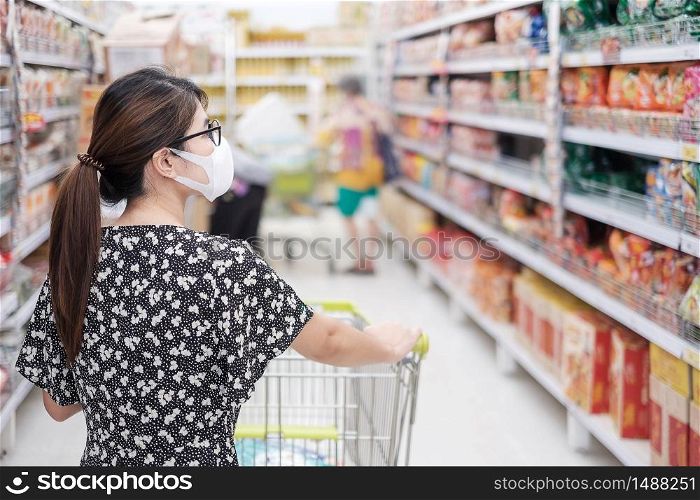 Asian woman wearing protective mask and shopping in supermarket or grocery, protect coronavirus inflection. social distancing, new normal and life after covid-19 pandemic