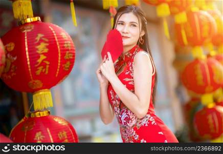 Asian woman wearing red cheongsam dress traditional decoration holding red envelopes in hand and lanterns with the Chinese text Blessings written on it Is a Fortune blessing for Chinese New Year
