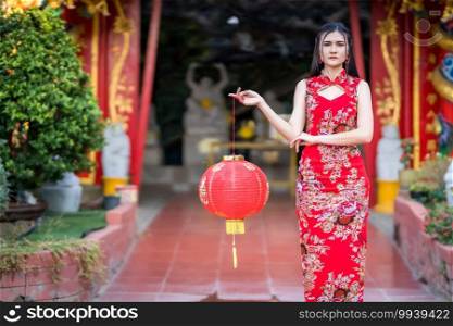 Asian woman wearing red traditional Chinese cheongsam decoration hold paper lanterns with the Chinese alphabet Blessings written on it Is a Fortune blessing compliment decoration for Chinese New Year
