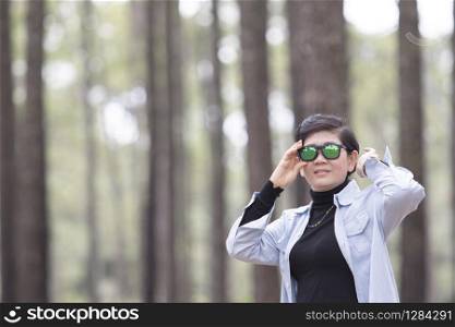 asian woman wearing sun glasses standing in pine wood forest relaxing emotion