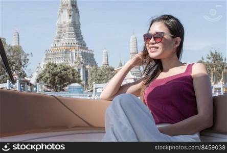 Asian woman wearing sunglasses while staying on boat with beautiful landscape. Travel and Lifestyle Concept.