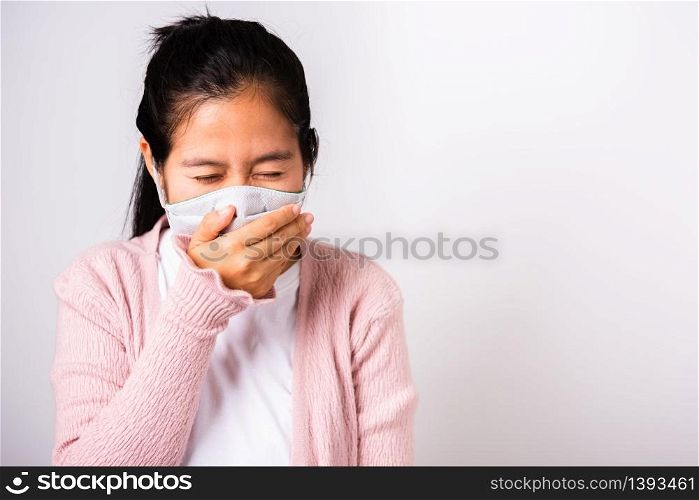 Asian woman wearing surgical protection cloth face mask hygiene against coronavirus and her sneeze hand close mouth, studio shot isolated on white background with copy space, COVID-19 concept