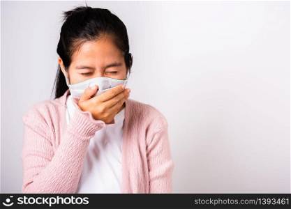Asian woman wearing surgical protection cloth face mask hygiene against coronavirus and her sneeze hand close mouth, studio shot isolated on white background with copy space, COVID-19 concept