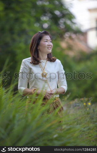 asian woman wearing thai period tradition clothes standing in green park