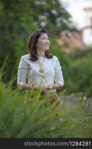 asian woman wearing thai period tradition clothes standing in green park