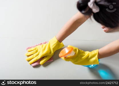 Asian woman wearing yellow rubber glover with cloth rag and detergent spray cleaning floor at home in living room, Female hands washing cleaner house worker, housework and housekeeping concept