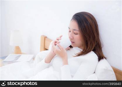 Asian woman with cup of coffee in bedroom with morning.