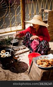 Asian woman with hat making food in the street. Asian woman with hat making food in the street Inle Lake Myanmar Burma