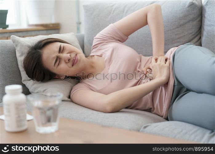 asian woman with menstruation and pain period cramps. young women having painful sleeping on sofa at her home