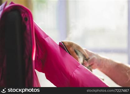 Asian woman Woman ironing down jacket with garment steamer