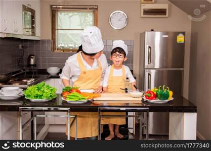 Asian woman young mother with son boy cooking salad food with vegetable holding tomatoes and carrots, bell peppers on plate for happy family cook food enjoyment lifestyle kitchen in home