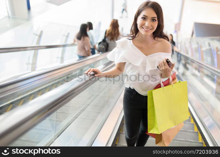 Asian women and Beautiful girl is holding shopping bags and using a smart phone and smiling while doing shopping in the supermarket/mall