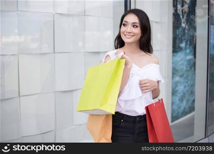 Asian women and Beautiful girl is holding shopping bags and using a smart phone and smiling while doing shopping in the supermarket/mall