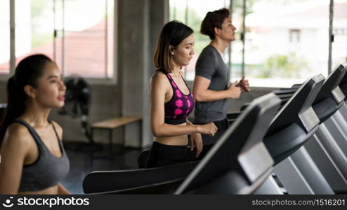 Asian women and man running exercise on treadmills in sport fitness gym with copy space for text. Healthy sporty friends run on machine. workout, training, bodybuilding lifestyle concept.