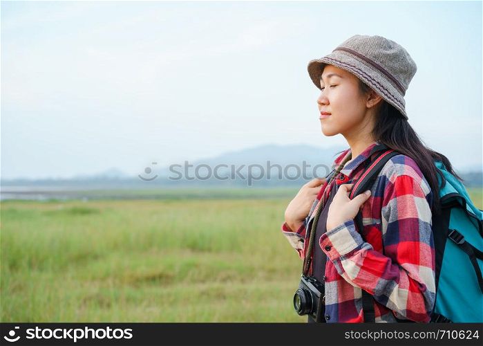 Asian women are closing their eyes and enjoying nature on the mountains and sky background. A young girl is traveling on summer vacation.