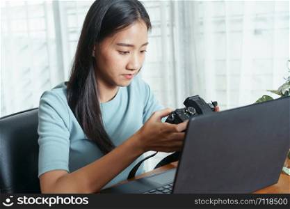 Asian women are using a digital camera and have a laptop placed on a table in a mobile office.