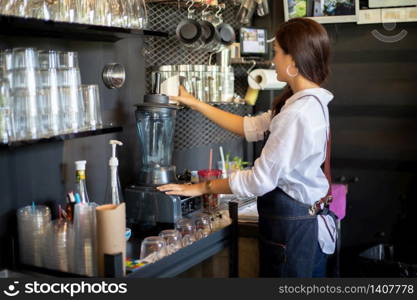 Asian women Barista smiling and using coffee machine in coffee shop counter - Working woman small business owner food and drink cafe concept