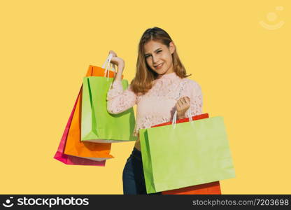 Asian women Beautiful girl is holding shopping bags and smiling on yellow background