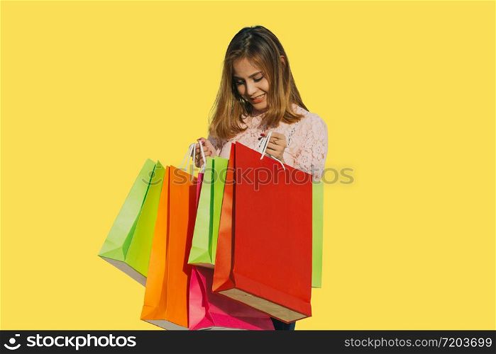 Asian women Beautiful girl is holding shopping bags and smiling on yellow background