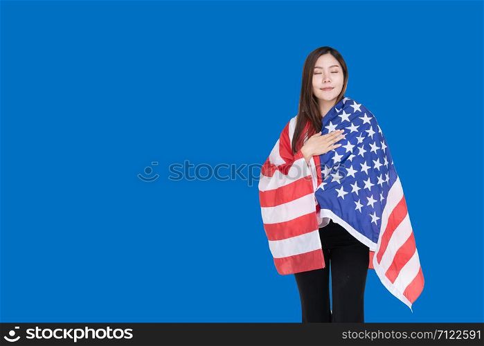Asian women covered with the US flag with a smile of joy on a blue background. Asian-American women are proud of the American flag.