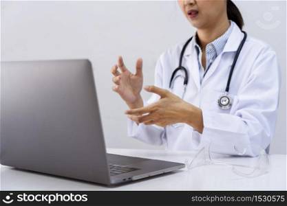 Asian women doctor using her laptop video call to explain medical consultation talking online with patient on webcam virtual conference from hospital, professional consultation telemedicine concept