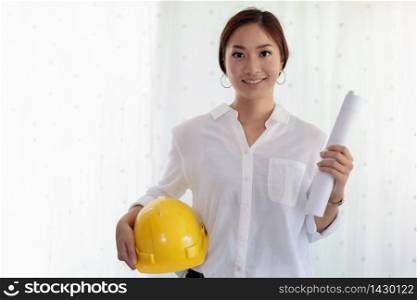 Asian women engineering holding blueprints , hard hat for working at office and white background