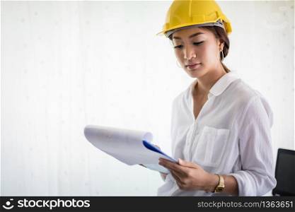 Asian women engineering inspecting and working and holding blueprints at office