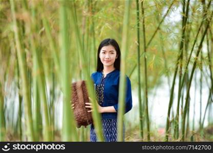 Asian women farmer in bamboo forest nature / Portrait of beautiful young woman happiness smile with basket for harvest agriculture in countryside village - dress tribe life