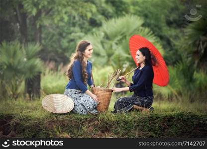 Asian women farmer in rice field nature / Portrait of beautiful woman happy smile hold red umbrella and basket for harvest agriculture in countryside village - Life young girl dress tribe